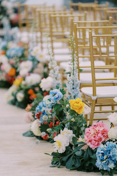 Aisle lined with bright floral arrangements and gold chairs, elegant detail shot by wedding photographer based in Toronto
