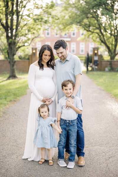 family of four standing together for maternity photos