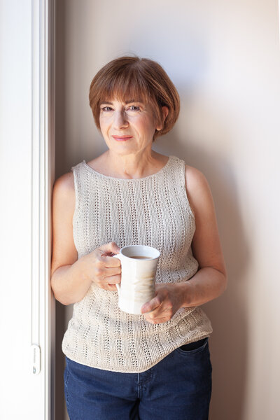 Middle age woman leaning against a door.