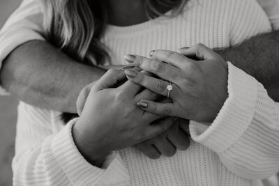 couples hold hands with engagement ring