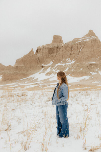 A woman looking to the side wearing a jean jacket.