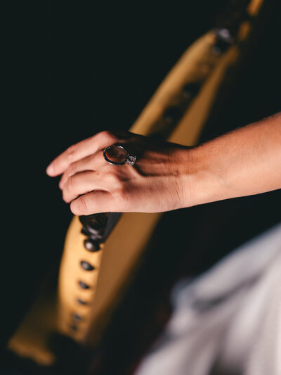 A wedding ring on top of the hand on a moody black background.