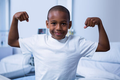 portrait-of-boy-flexing-his-muscles-in-ward-2023-11-27-05-11-29-utc