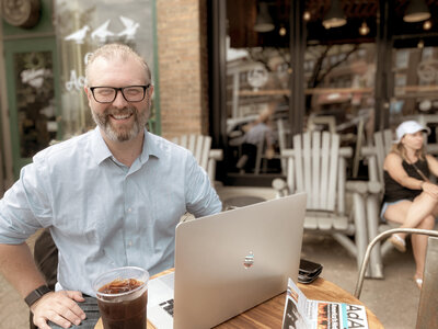 Smiling man sitting at coffeeshop with computer