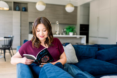 Woman sitting on blue couch reading a book