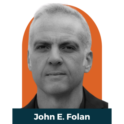 A black and white headshot of john. He has ligh colored hair a nd a black shirt
