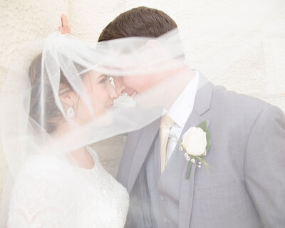 Wedding couple, softly lit, happily looking at each other under a veil