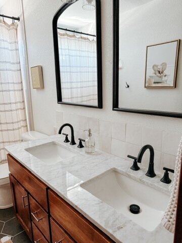 Bathroom interior with double vanity, black hardware, and soft neutral styling by KSC Interiors.