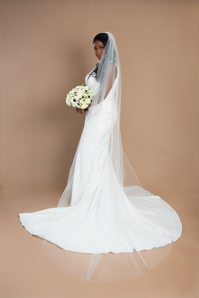 bride wearing a cathedral length veil and holding a white and blush bouquet