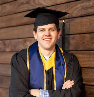 A young graduate wearing a cap and gown at his cllege graduation.