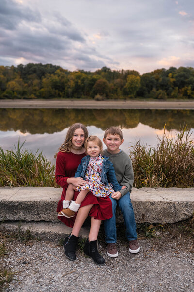 Family with grown children stands  near creek in the autumn