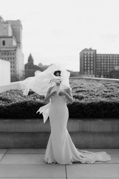 Black and white image of bride with veil blowing over her face