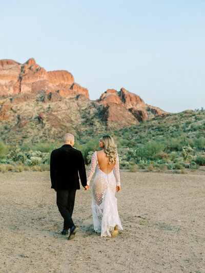 bride and groom walk in the desert together