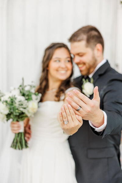 bride and groom holding up their wedding rings