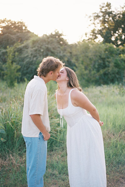 Couples kisses in Texas field as the sun sets