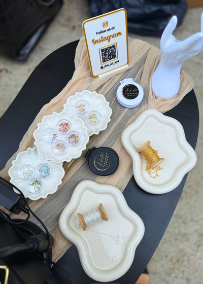 Stack of gold and beaded permanent bracelets on wrist with charm detail.