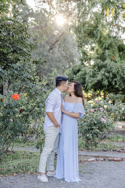 Couple sharing intimate kiss during family portrait session at Fremont Rose Garden in Bay Area