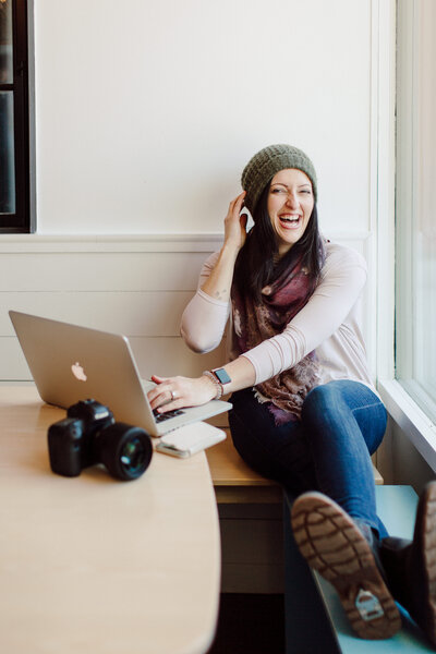 woman sitting at laptop while laughing