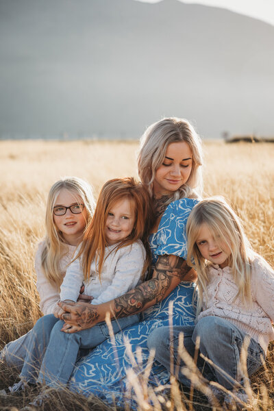 Family photoshoot in Wanaka. a family sitting in the long grass - captured by Bie