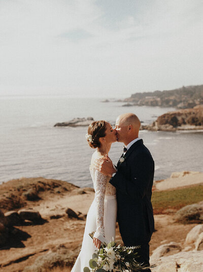 bride-and-groom-kissing-in-front-of-water