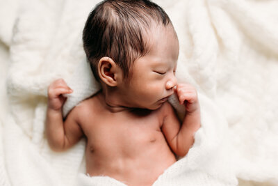 Newborn baby asleep in a white wrap