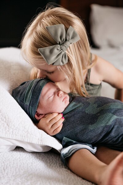 Sweet sister kissing newborn baby