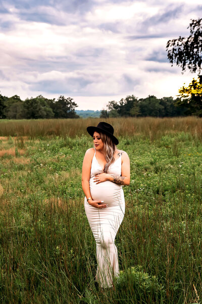 Pregnant woman in white gown standing in a field in Stamford, CT