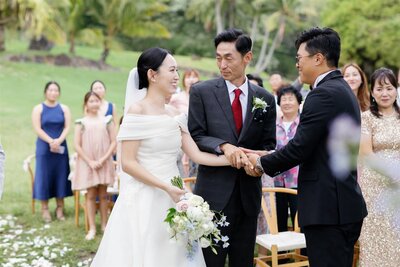A person handing off someone to their partner during their wedding ceremony 