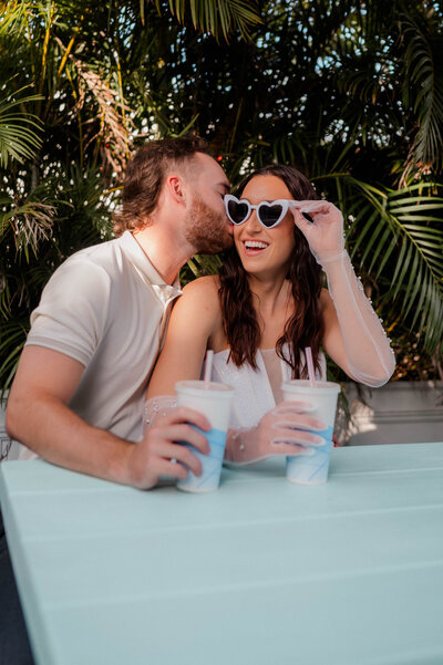 A couple leans into each other and smiles at the camera.