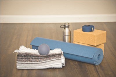 A yoga matt, blanket, water bottle and blocks sitting in the studio