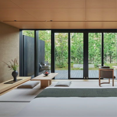 Image of the Susuki Hotel room at the Aman Kyoto, a bed looking out at floor to ceiling windows with green nature outside