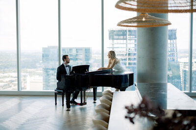 Couple sharing a modern love-story moment at a grand piano with sweeping city views at High Rise in downtown Austin.