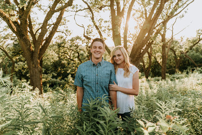 couple holding hands and smilling during engagement session in Hitchcock Nature Trails, Honey Creek Iowa. Photo by wedding photographer,  Kaitlyn Neeley