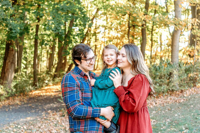 Connecticut family photographer captures loving family of three in coordinating fall colors during golden hour outdoor session