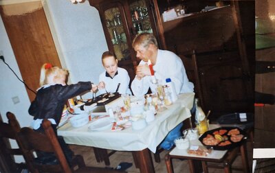 Foto jaren 90 vader zit met twee dochters aan tafel te gourmetten in oud bruin interieur