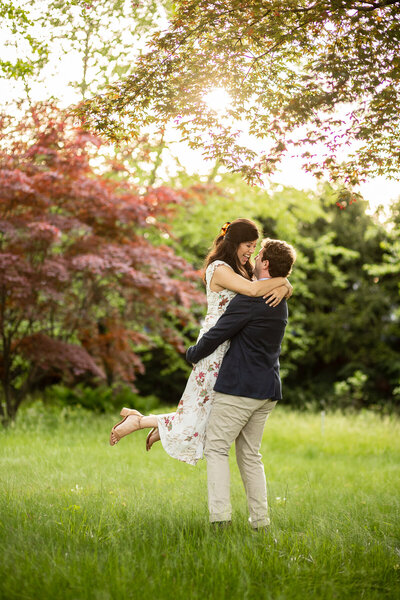 Adam lifts katie and spins her around at their beautiful outdoor engagement session