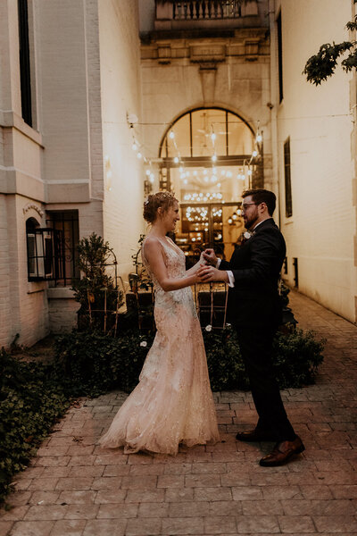 Bride and Groom hold hands in courtyard at Iron Gate Restaurant wedding in Washington DC