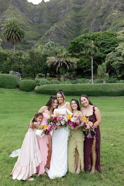 A person in a wedding dress smiling with her wedding party around them 