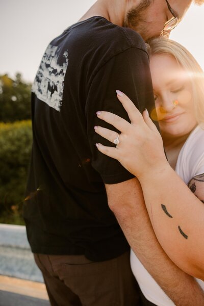 Couple in an embrace, with focus on engagement ring.