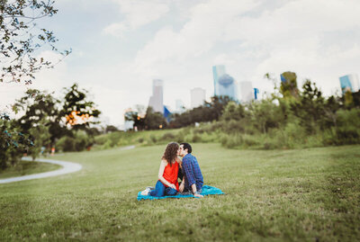 Couple kissing during an outdoor engagement session with a city skyline backdrop in Orlando. 