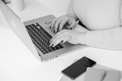 Hands typing on a laptop in the Sarah Shuttle Luxury Brands studio, working on a premium brand identity