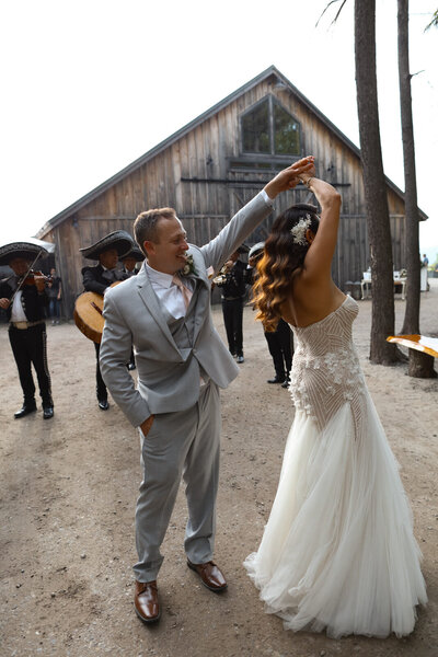 bride and groom dancing in front of a barn