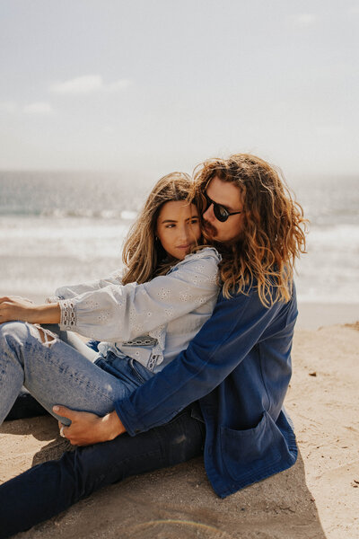Couple embrace sitting on beach