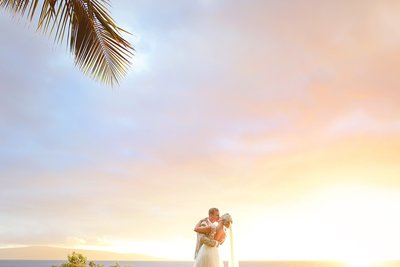 bride and groom kiss under a sunset sky after eloping on maui with love and water photography