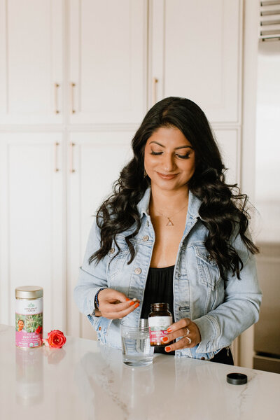 Nutrition coach Radhika holding supplements in a kitchen