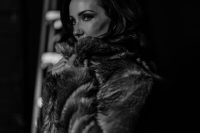 A black and white side profile photo of Juliet Trnka in a fur coat. Up close