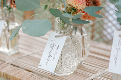 Escort card tags with calligraphy on bud vases for wedding at Smith Farm Gardens in Connecticut
