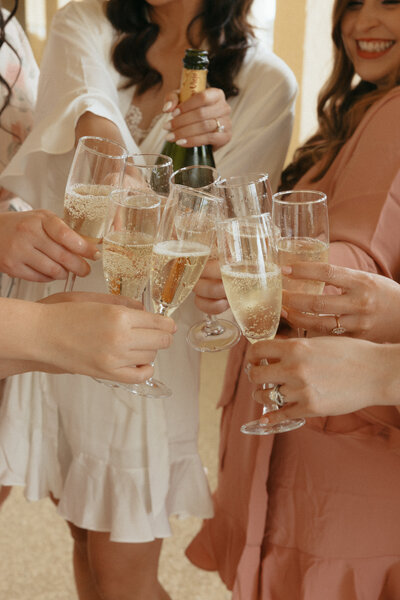 Bridesmaids raising champagne flutes in celebration during wedding prep, part of a full-service wedding weekend planned by The Eventful Gals.