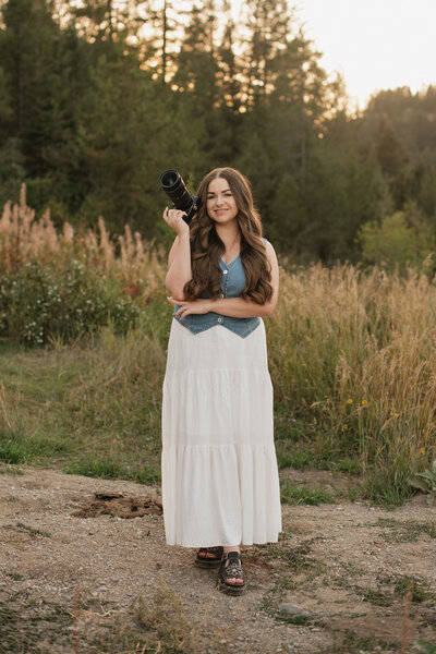 Branding photo for Bailee Freeman Photography with a black blazer and a Nikon camera in front of her. 