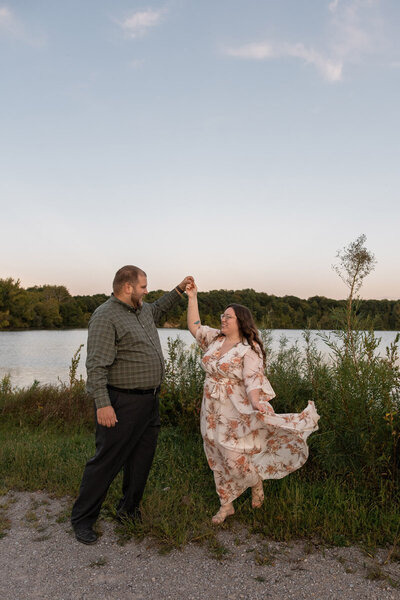 Bride and groom hold hands in front of tall trees at sunset
